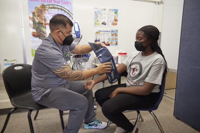 Nurse on Oahu takes a student's blood pressure