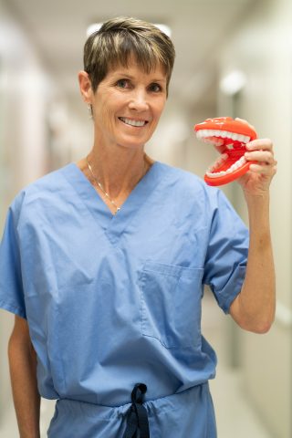 Deborah Mattheus in scrubs holding a model mouth