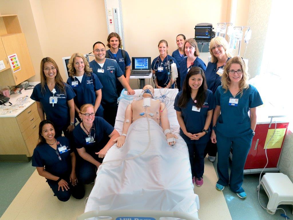 students pose for group photo with dummy patient 