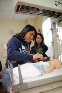 Students with infant manikin in sim lab